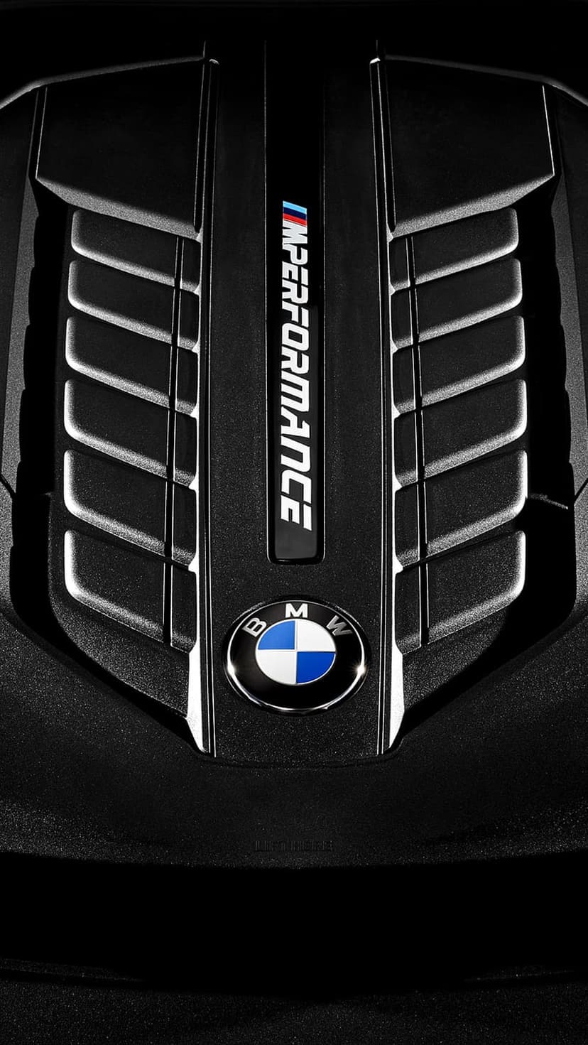 BMW M Performance engine cover with a textured black surface and a central blue and white circular emblem.