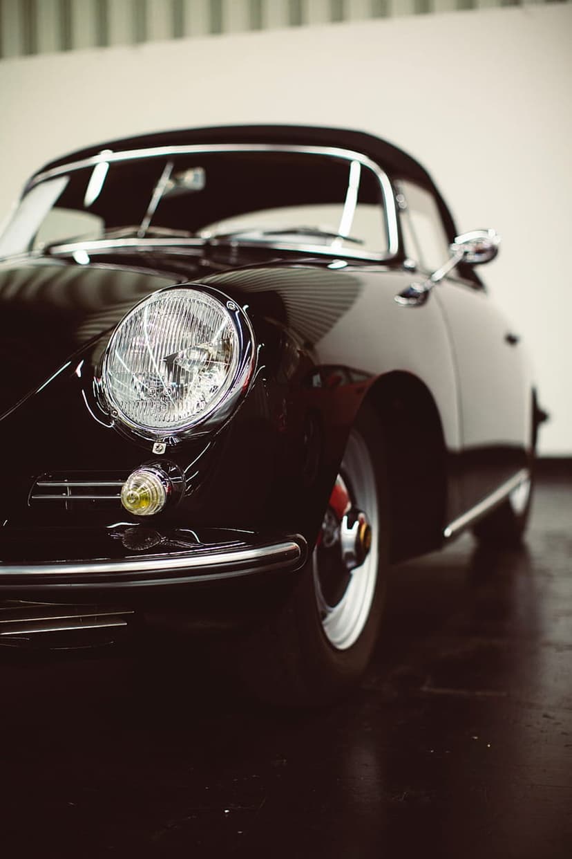 Porsche 356 Speedster front bumper with a round chrome headlight and yellow turn signal on polished black paint.