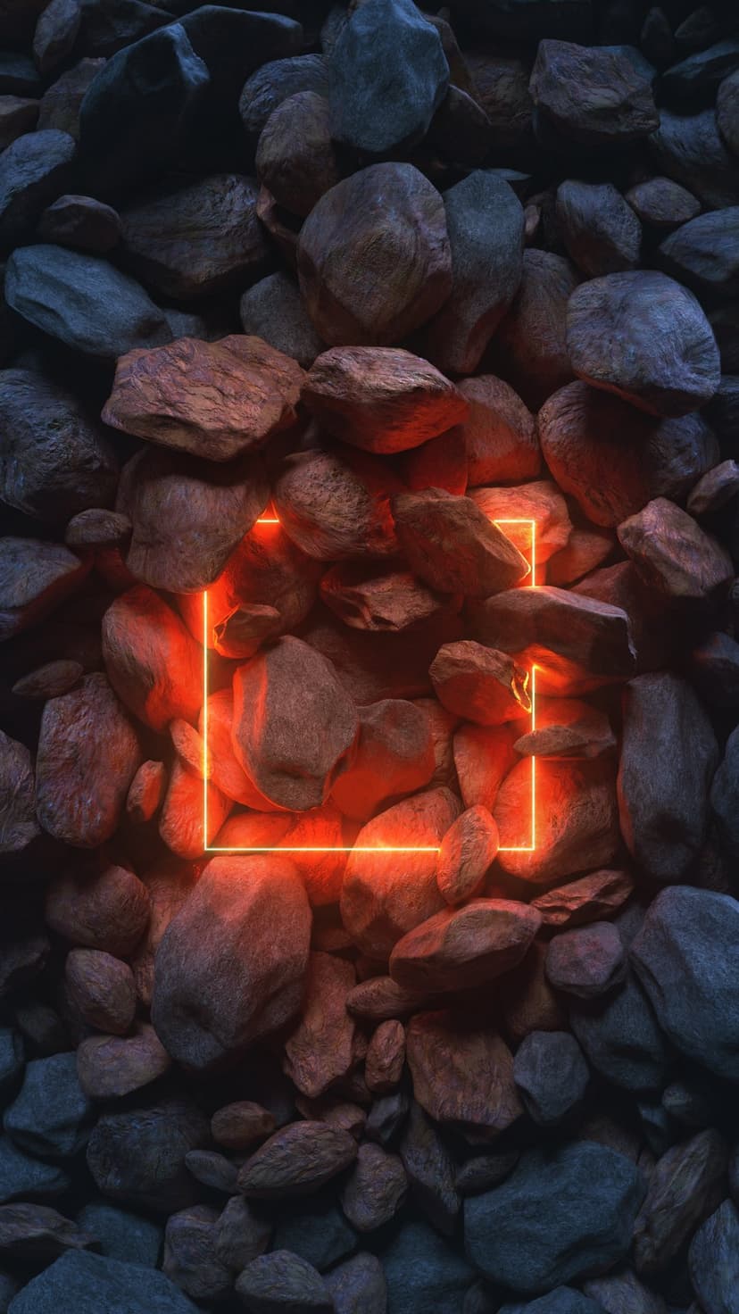 Glowing orange neon square frame resting on a pile of textured gray and brown volcanic rocks with deep shadows.