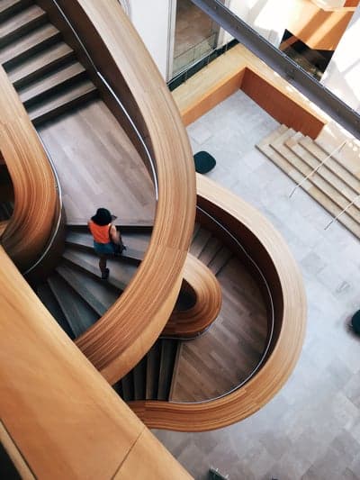 Woman walks up modern wooden spiral staircase