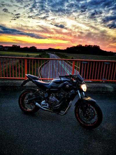 Motorcycle on Bridge During Sunset with Dramatic Sky