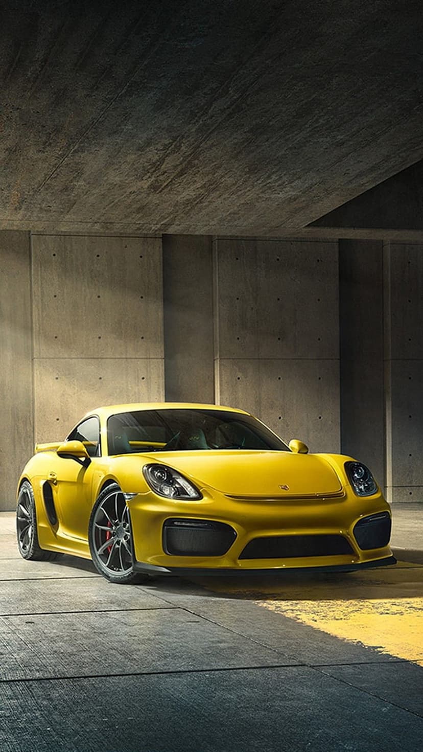 Yellow Porsche Cayman GT4 parked in a minimalist concrete garage with industrial textures and low-angle lighting.
