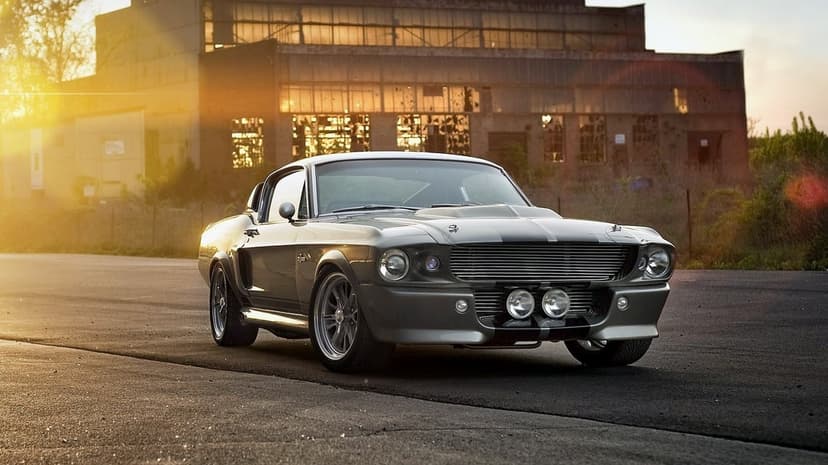 Silver Shelby GT500 Mustang Eleanor parked in front of an industrial factory during a golden hour sunset.