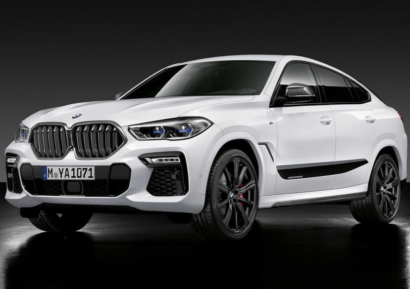White BMW X6 M Performance SUV with black wheels and blue headlights against a dark studio background.