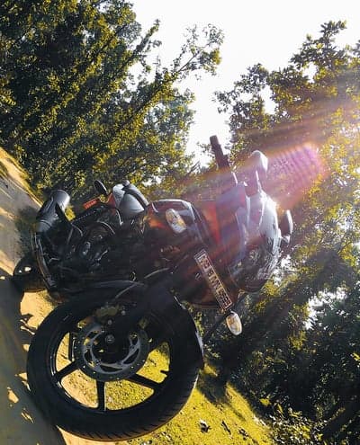 Motorcycle parked on grassy slope with sun glare