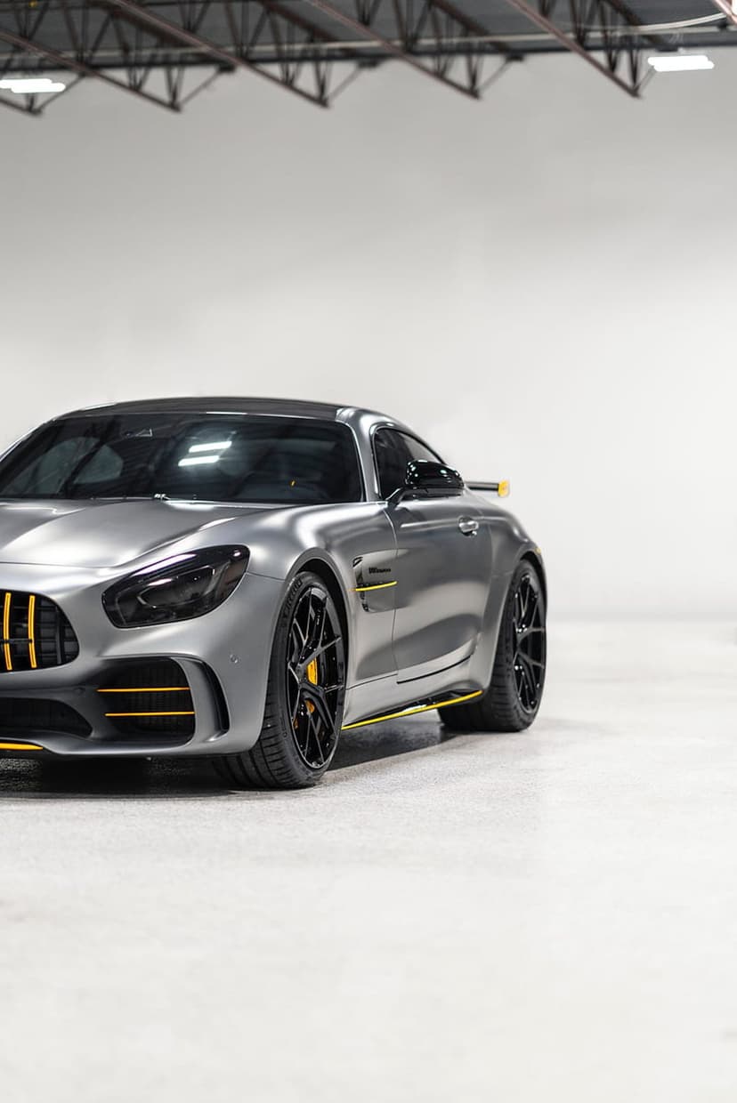Mercedes-AMG GT R in matte grey with yellow accents and black wheels parked in a clean minimalist indoor garage.