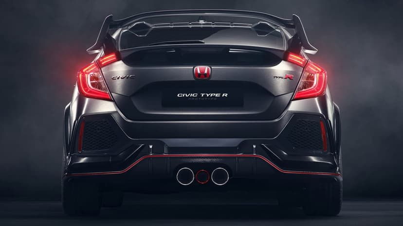 Rear view of a dark grey Honda Civic Type R Prototype with glowing red LED taillights and triple exhaust.