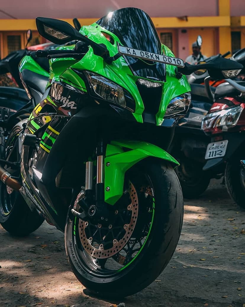 Kawasaki Ninja motorcycle with lime green fairing, dual headlights, and mechanical wheel details parked outdoors.