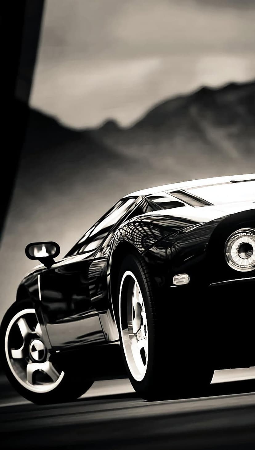 Classic sports car with a glossy finish stands before hazy mountains in a high-contrast monochrome landscape.