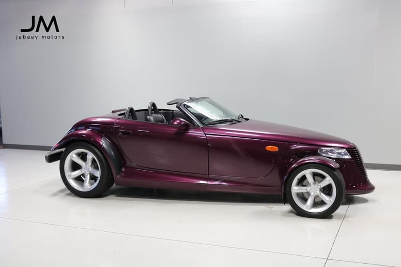 Purple Plymouth Prowler convertible with silver wheels in a minimalist white and grey studio space.