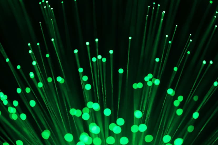 Glowing green fiber optic strands with luminous tips and soft bokeh circles against a dark background.