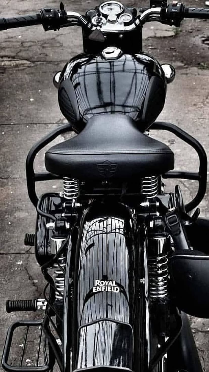 Royal Enfield motorcycle rear view featuring a black leather seat, chrome coil springs, and a polished fender.
