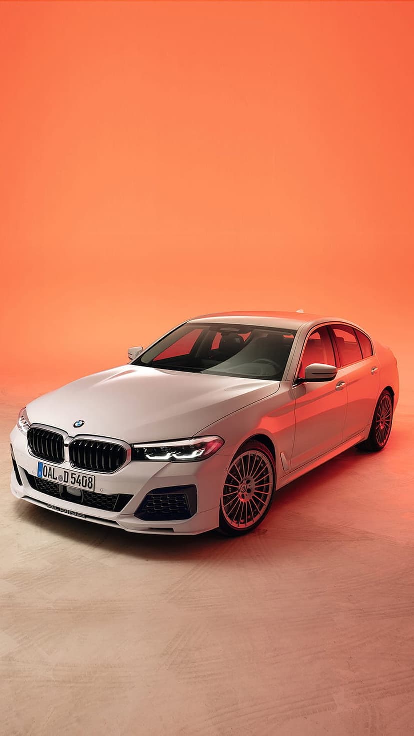 White BMW sedan features a glowing orange background with visible front grille, headlights, and alloy wheels.