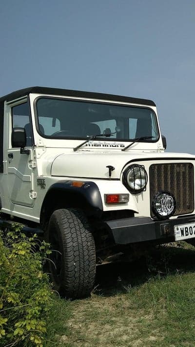 White Mahindra Thar off-roading adventure in lush green landscape