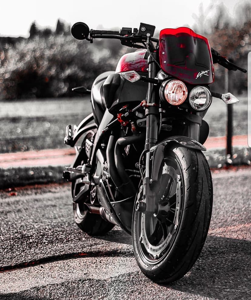 Black motorcycle with red accents and dual headlights captured from a low angle against a blurred background.