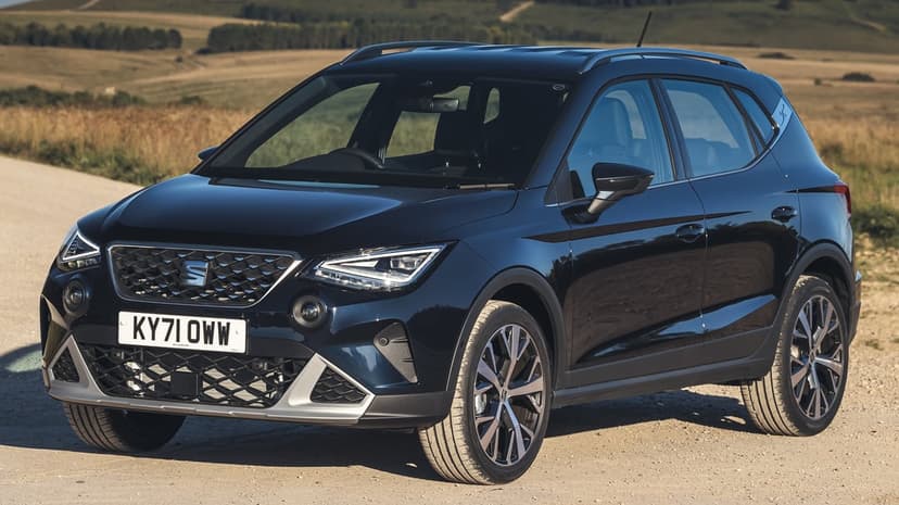 Dark blue SEAT Arona SUV parked on a dirt road with rolling hills and sunset lighting in the background.