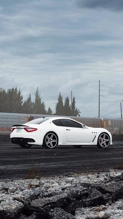 White Maserati GranTurismo parked on asphalt with stormy sky