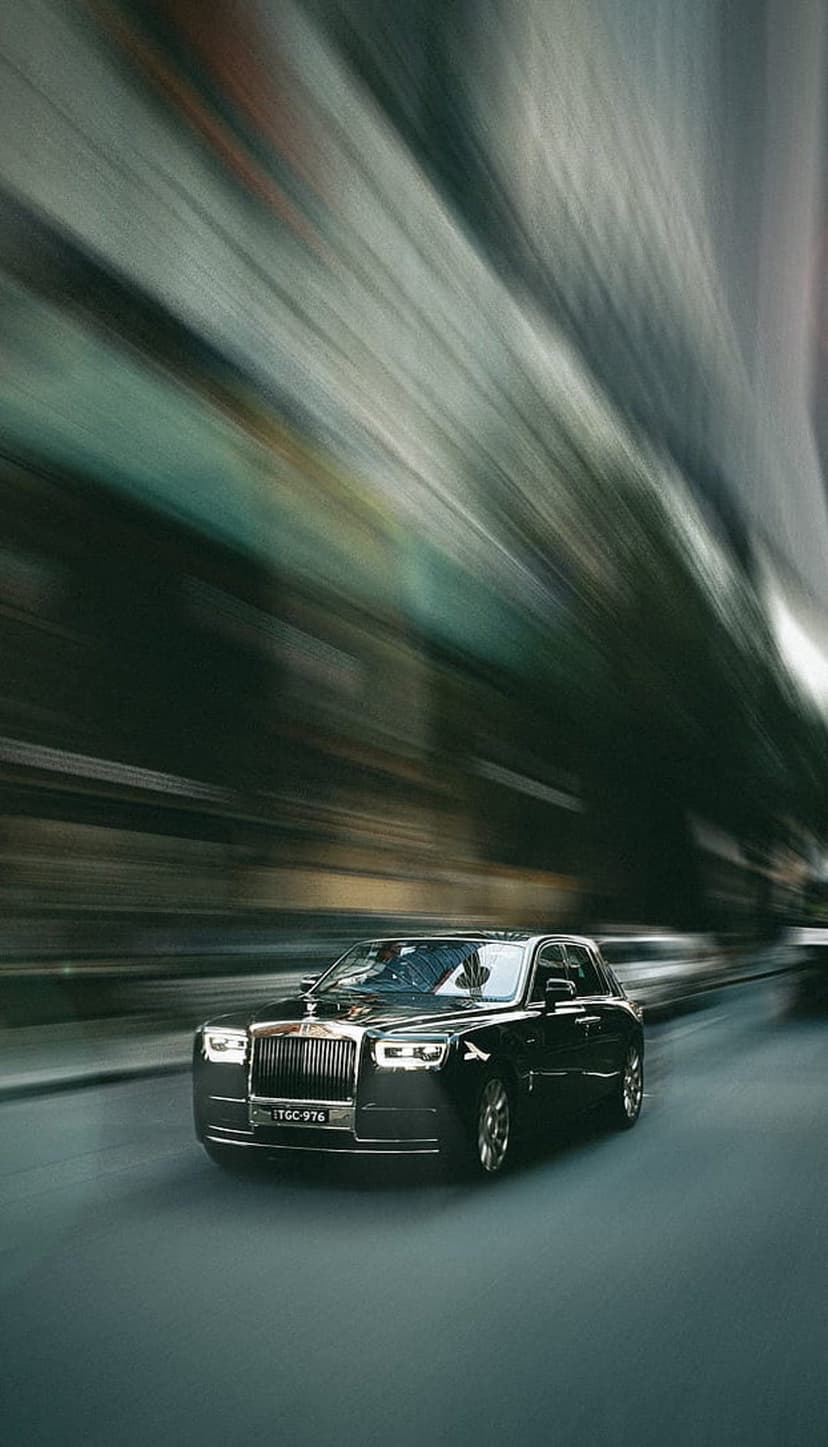 Rolls-Royce Phantom racing through a dark urban tunnel with motion blur and glowing golden overhead light streaks.