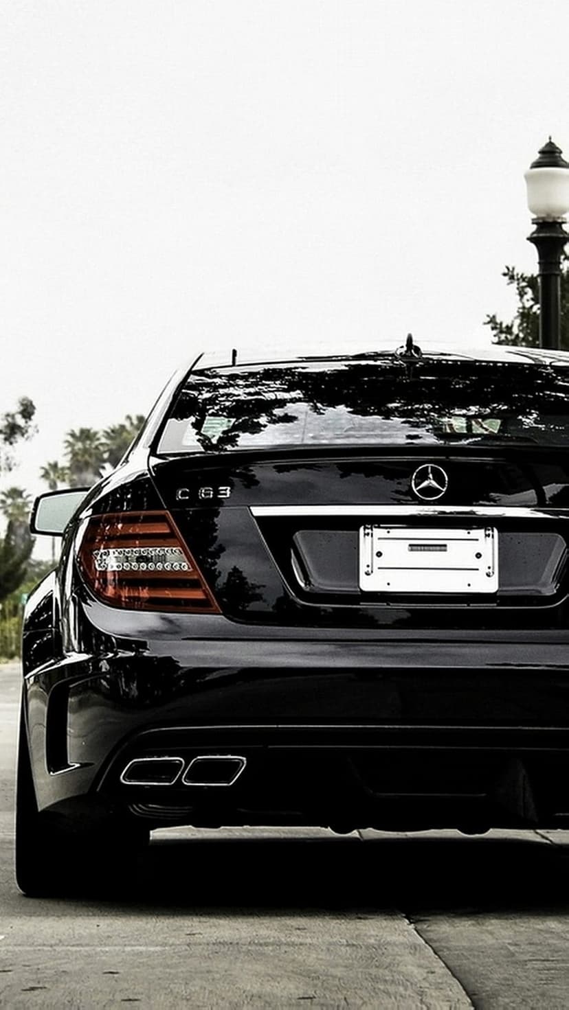 Black Mercedes-Benz C63 AMG rear view featuring quad exhaust tips, chrome badging, and glowing LED taillights.