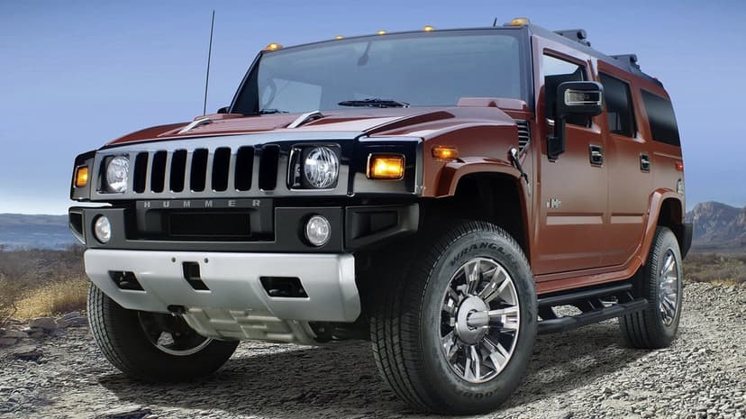Metallic brown Hummer H2 SUV parked on rocky desert terrain against a clear blue sky under bright daylight.