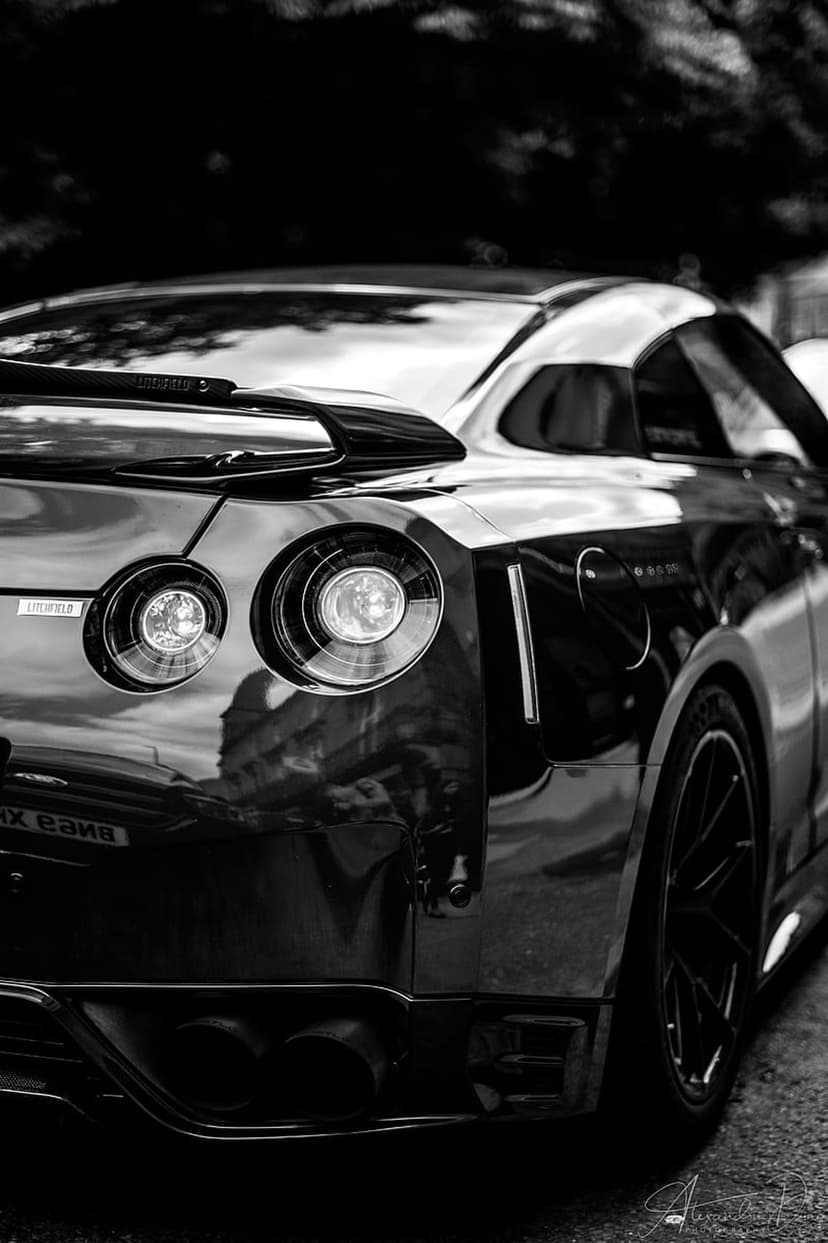 Nissan GT-R rear view showing iconic circular taillights and rear wing in high-contrast black and white photography.