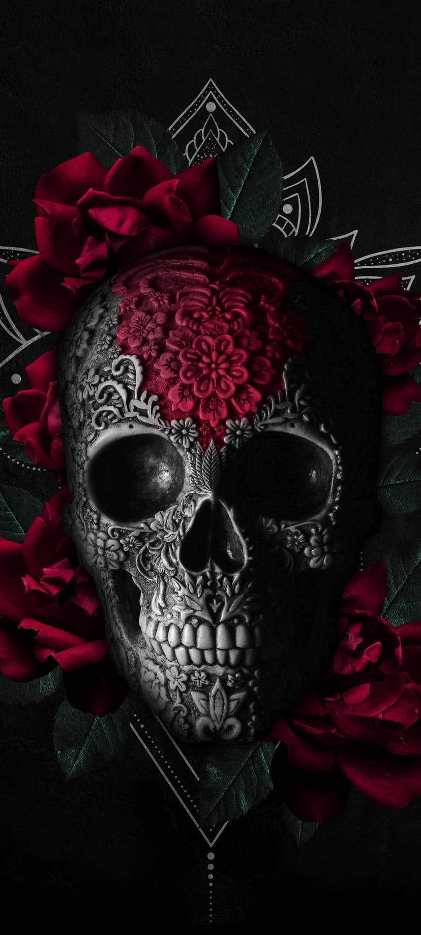Sugar skull with red rose carvings and emerald leaves set against a dark background with white mandala patterns.