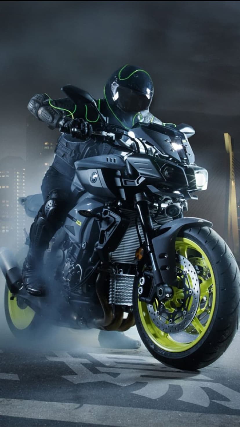 Yamaha MT-10 rider performs a smoky burnout on an urban street at night with glowing yellow wheels.
