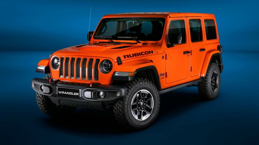 Orange Jeep Wrangler Rubicon with black fenders and off-road tires against a blue gradient studio backdrop.