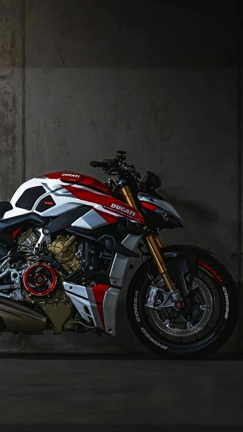 Ducati motorcycle with red and white fairings parked against a gray textured concrete wall in vertical view.