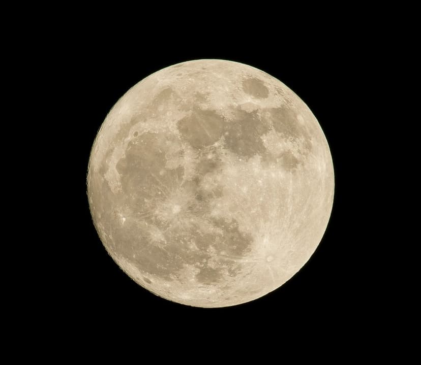 Detailed full moon with gray craters and highland textures centered against a pitch black night sky background.