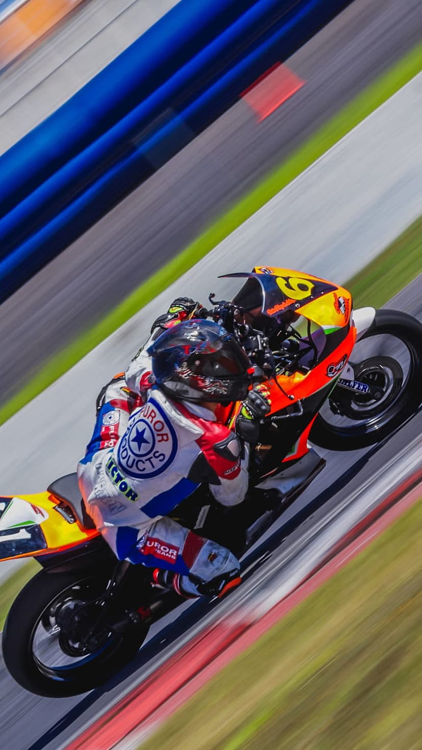 Motorcycle racer leaning a yellow sportbike into a sharp turn with intense motion blur on a professional track.