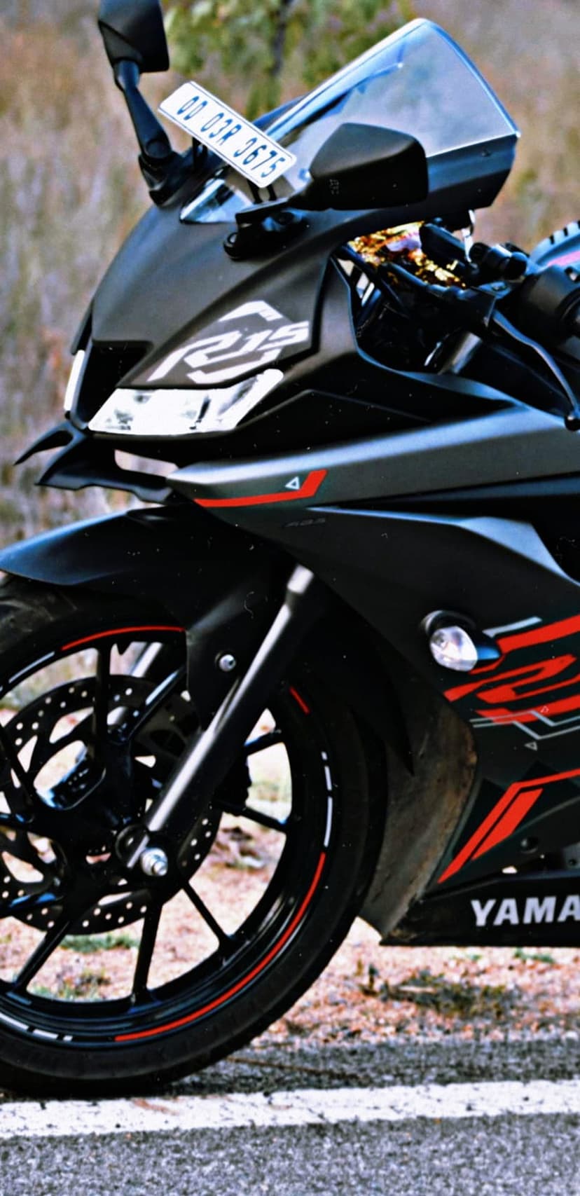 Black Yamaha R15 sportbike with red accents, sharp LED headlights, and front disc brakes in a vertical view.
