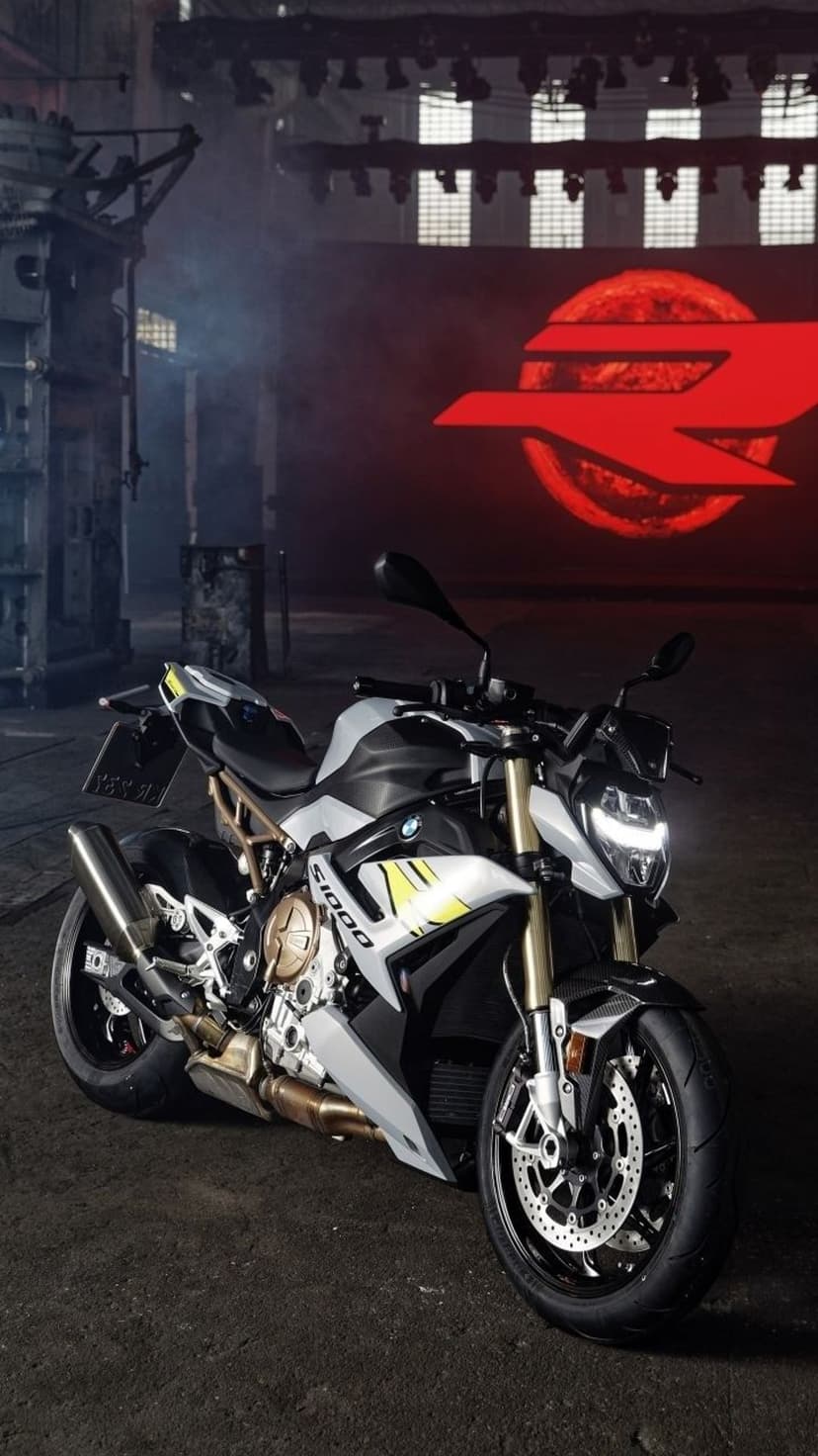 BMW S1000R motorcycle with yellow accents parked in a dark warehouse featuring red neon lighting and concrete walls