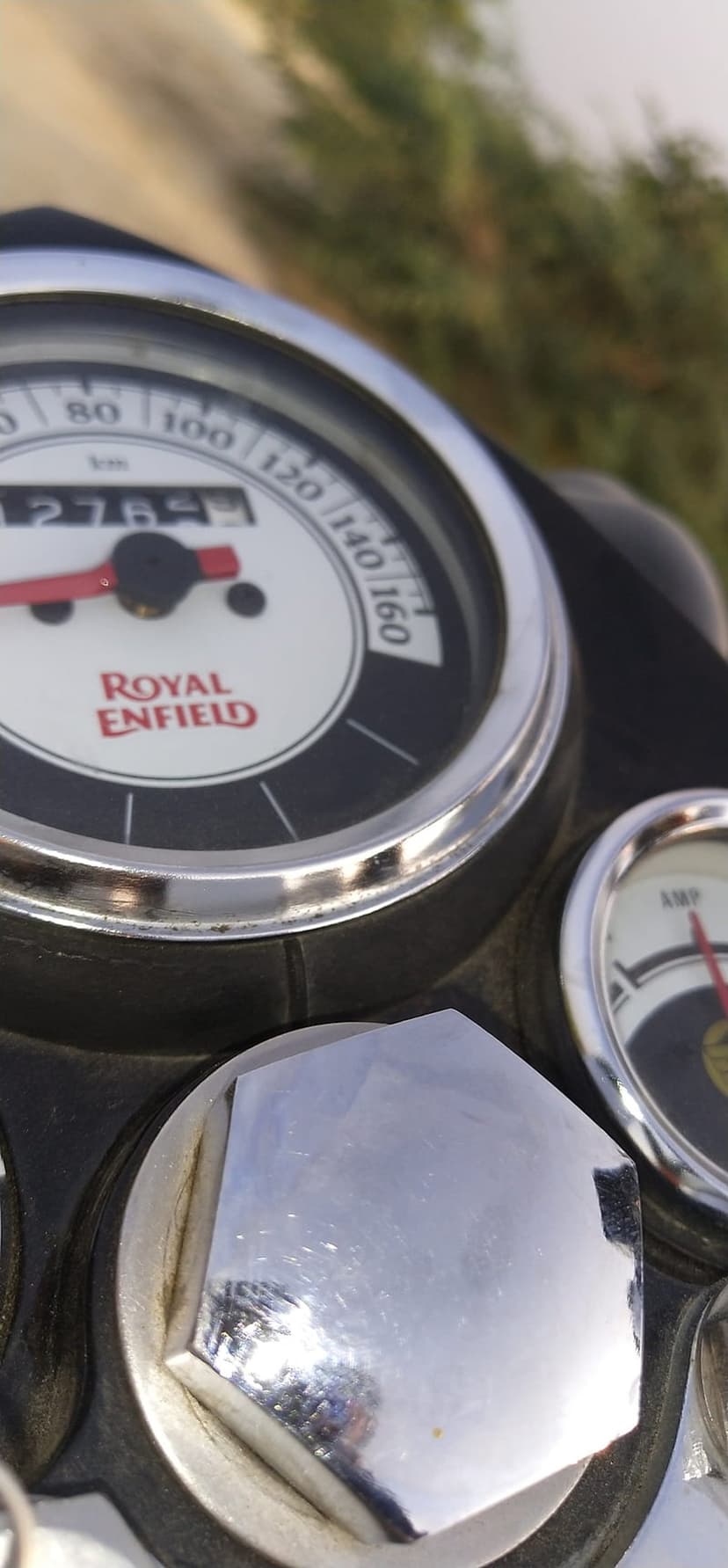 Royal Enfield speedometer and ammeter gauges featuring polished chrome housing and analog odometer readings.