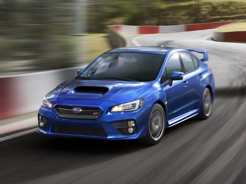 Blue Subaru WRX STI racing through a sharp turn on a track with motion blur and sun glinting off the roof surface.