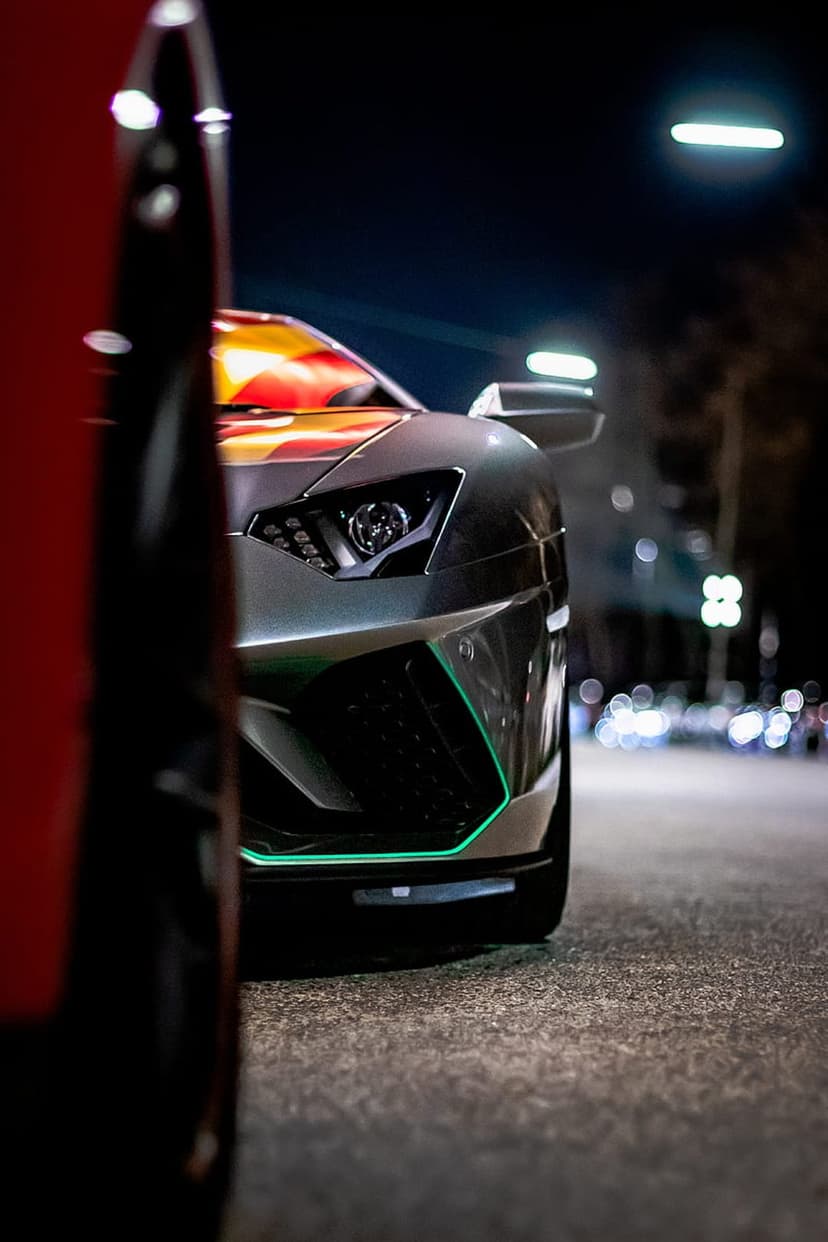 Lamborghini Aventador with neon green splitter and grille parked on a city street at night with bokeh lights.