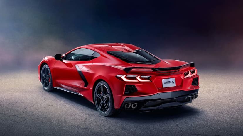 Red Chevrolet Corvette C8 supercar rear view with glowing taillights in a dark studio with blue lighting.