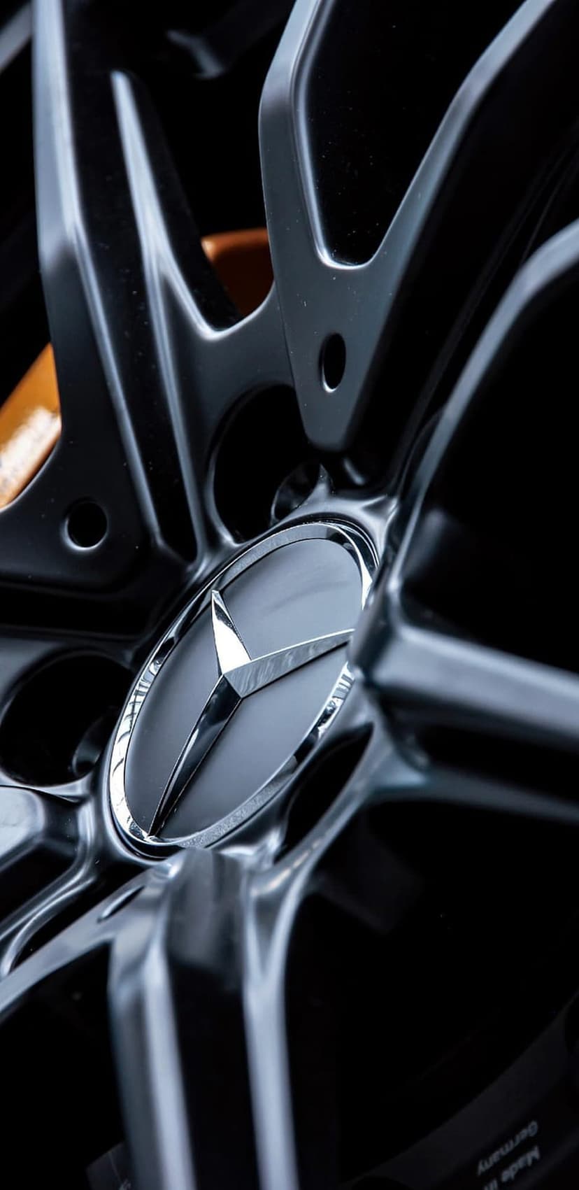 Mercedes-Benz alloy wheel featuring a silver three-pointed star logo and a bright orange brake caliper.