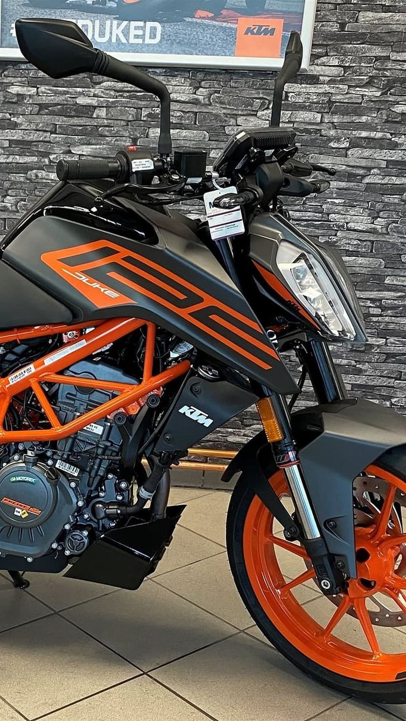 KTM Duke 390 motorcycle features a bright orange trellis frame, LED headlight, and branded fuel tank accents.