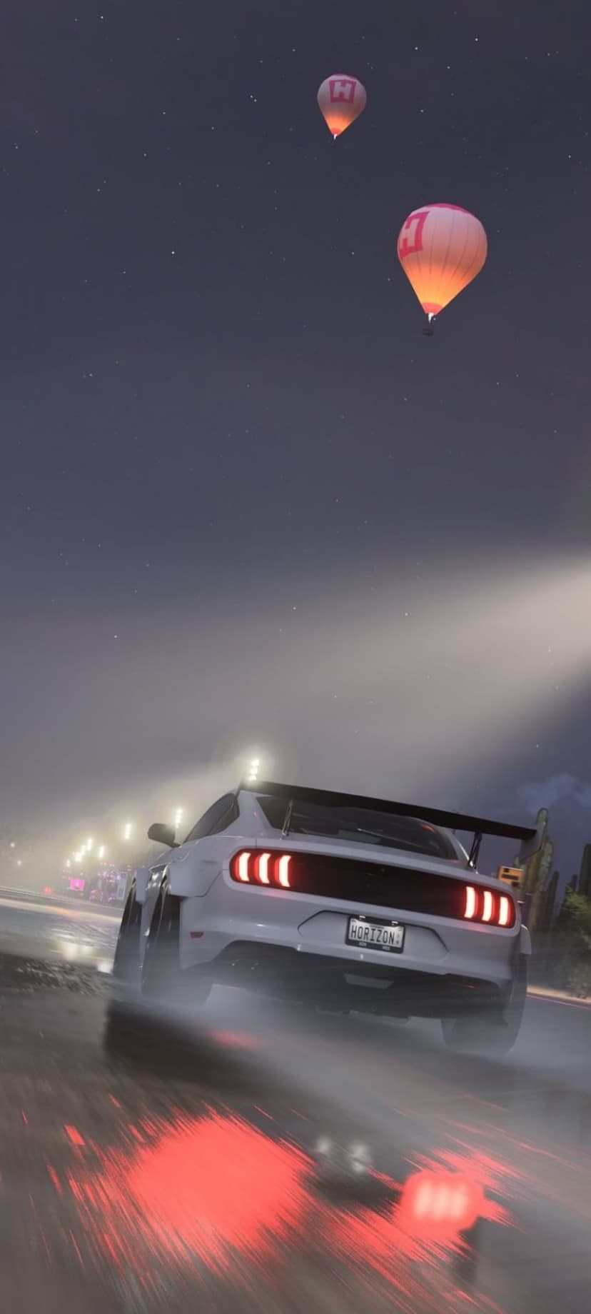 White Ford Mustang racing on a wet night road with red taillights below two glowing hot air balloons in the stars.