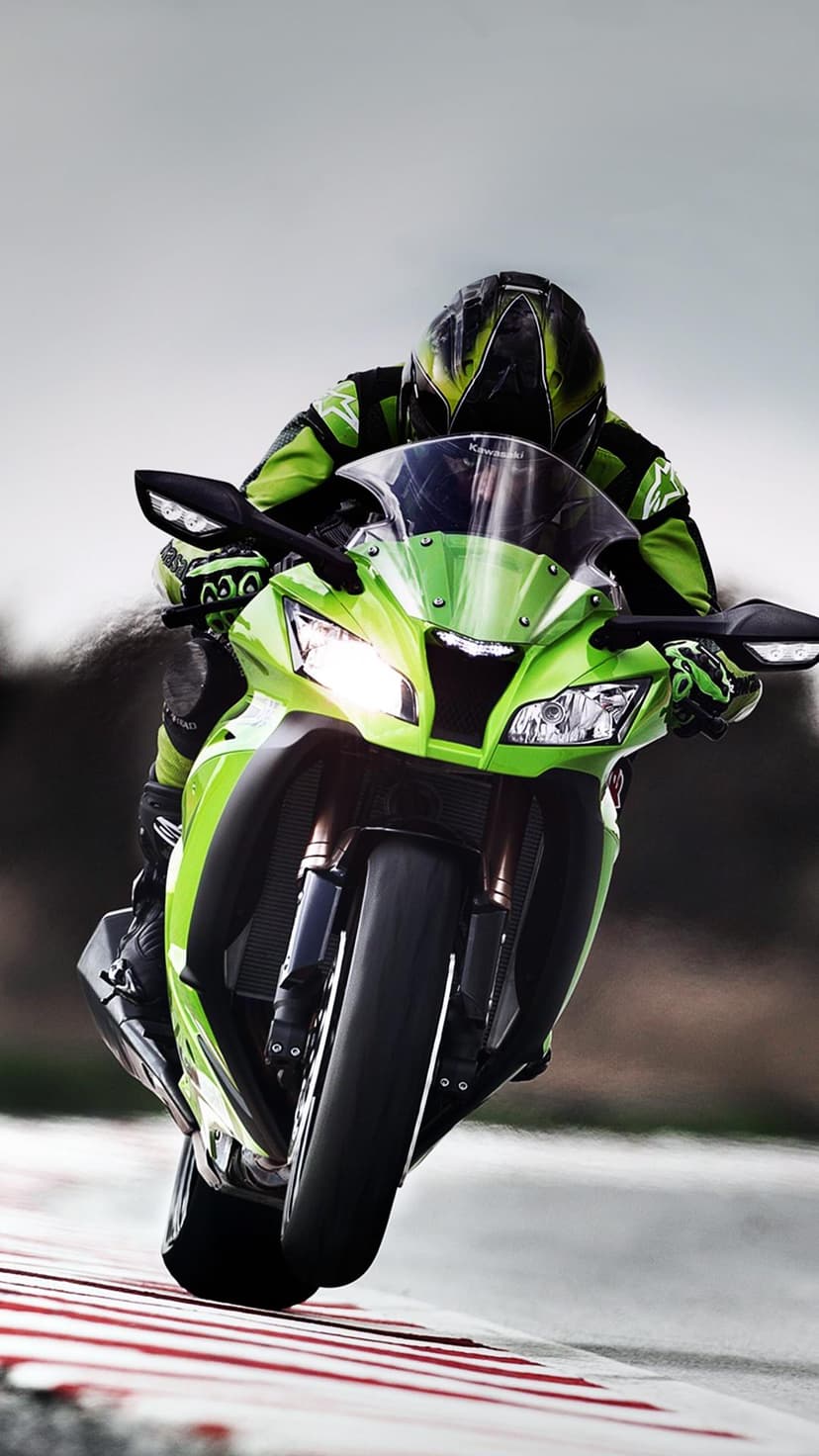Motorcycle racer in a green suit leans a sportbike into a track turn with blurred background motion.