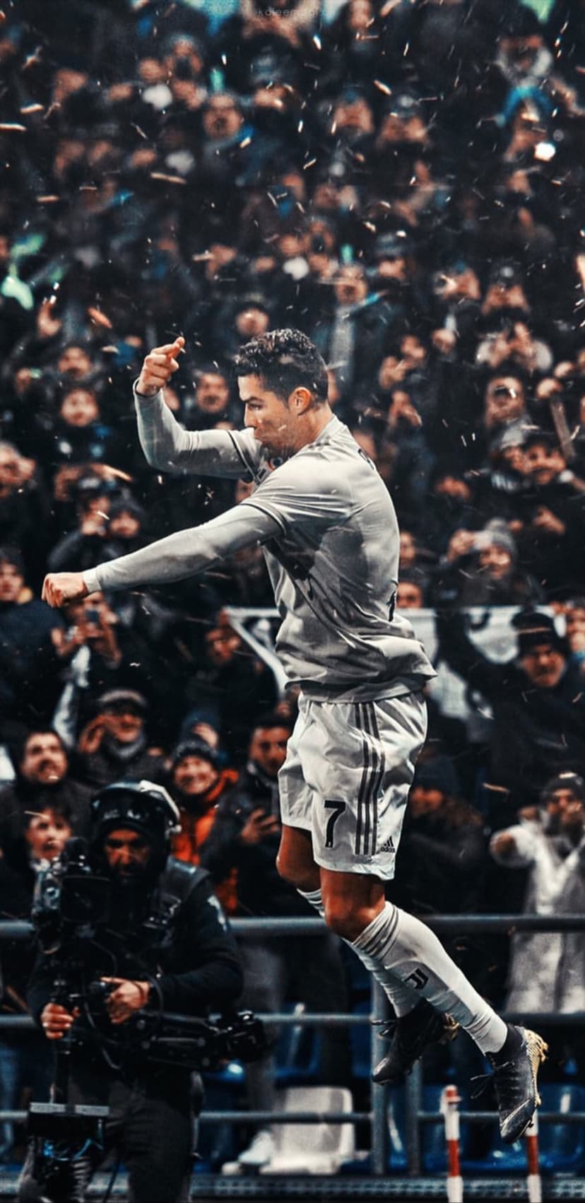 Cristiano Ronaldo leaps in mid-air with arms wide amidst falling confetti and a cheering crowd in a stadium.