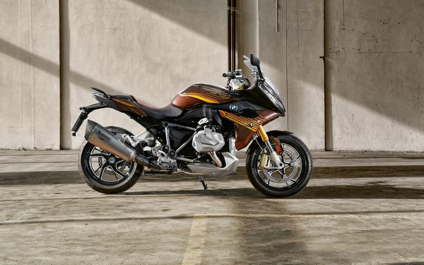 A custom brown and gold BMW R 1250 RS motorcycle parked against a concrete wall with sharp sunlight shadows.