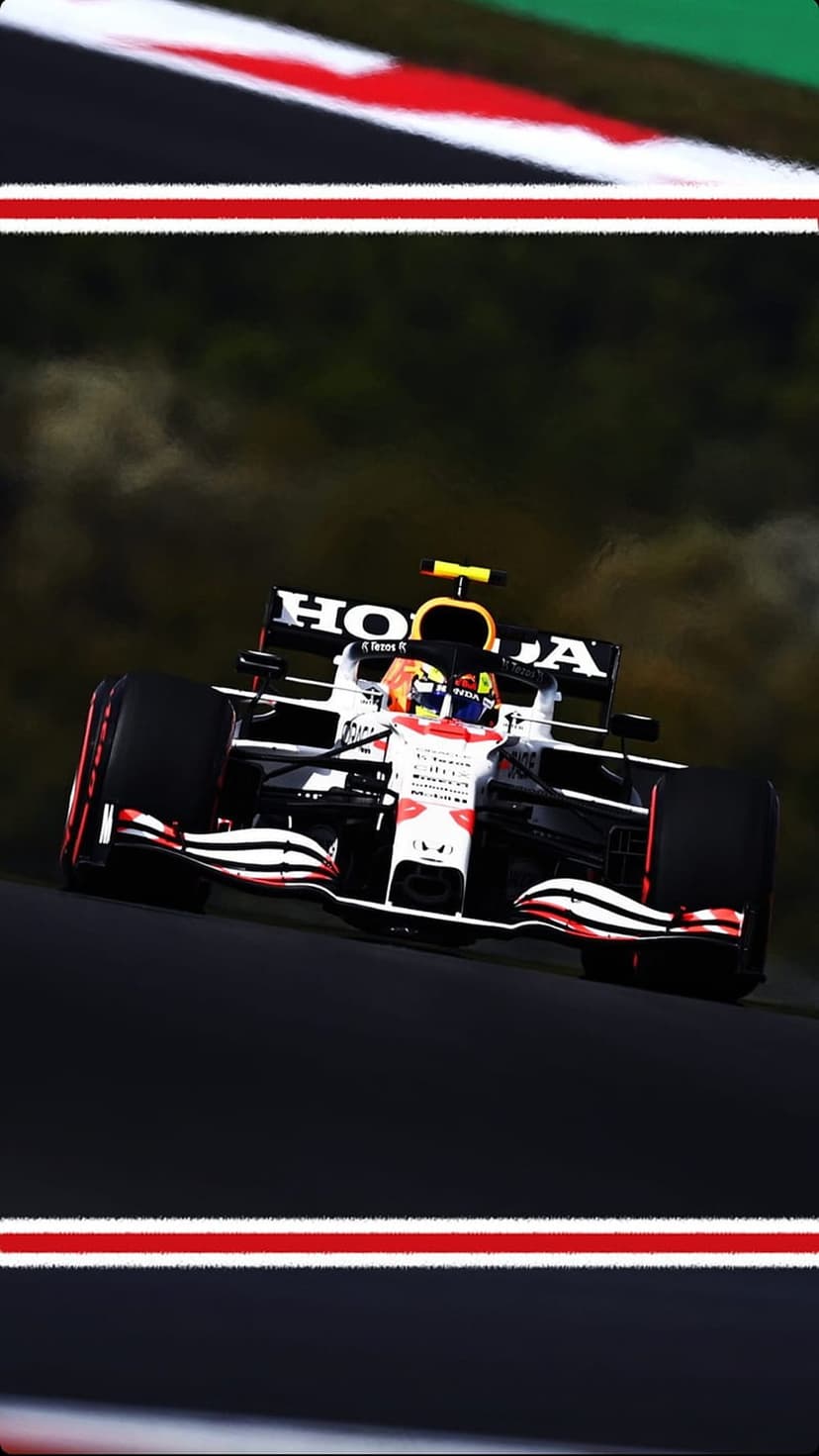 Red Bull Racing Formula 1 car kicks up tire smoke while cornering at high speeds on a professional race track.