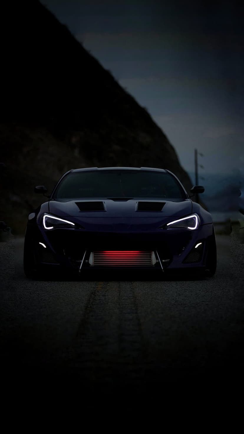 Dark purple sports car with C-shaped white LED headlights and a glowing red intercooler on a misty night road.