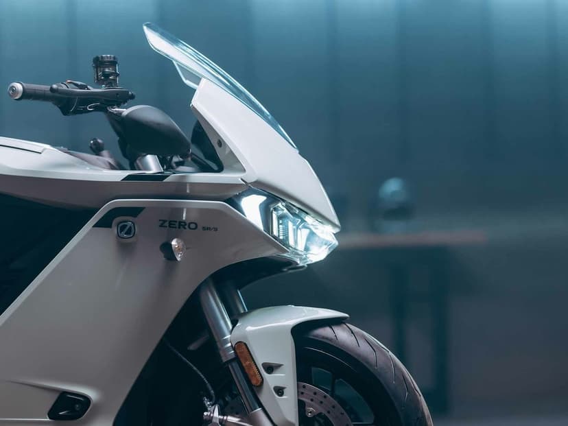 White Zero SR/S electric motorcycle front fairing with a glowing LED headlight and aerodynamic windscreen.