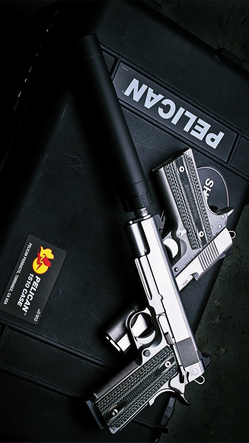 Two silver handguns, one with a silencer, lie on a black Pelican case with textured grips and metallic finishes.