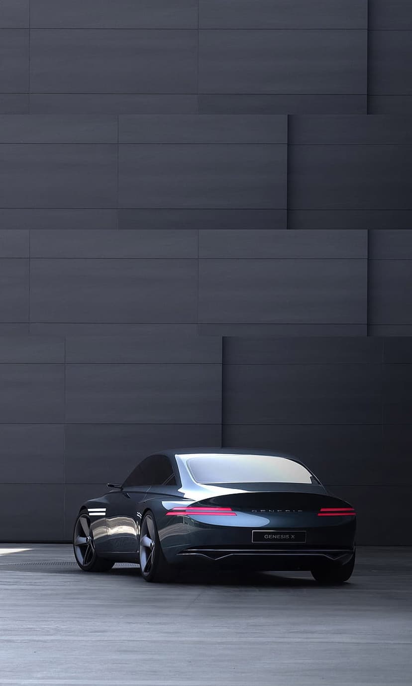Genesis X concept car rear view showing horizontal LED taillights against a dark textured architectural wall.