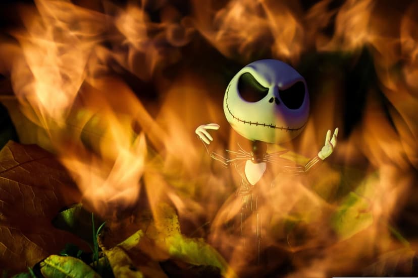 Jack Skellington doll surrounded by glowing orange autumn leaves under a dramatic, high-contrast warm light.