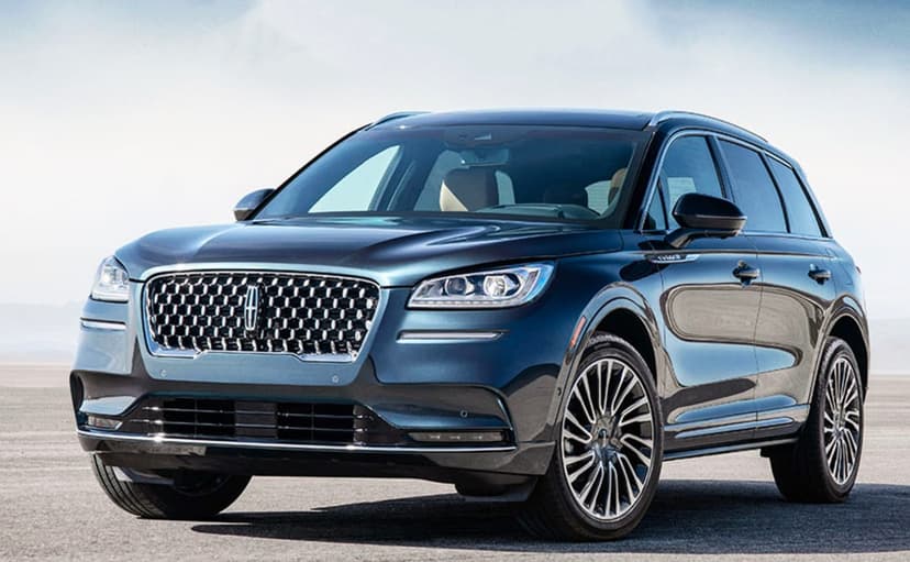 Blue Lincoln Corsair SUV with a chrome grille parked on a flat desert terrain under a bright clear sky.